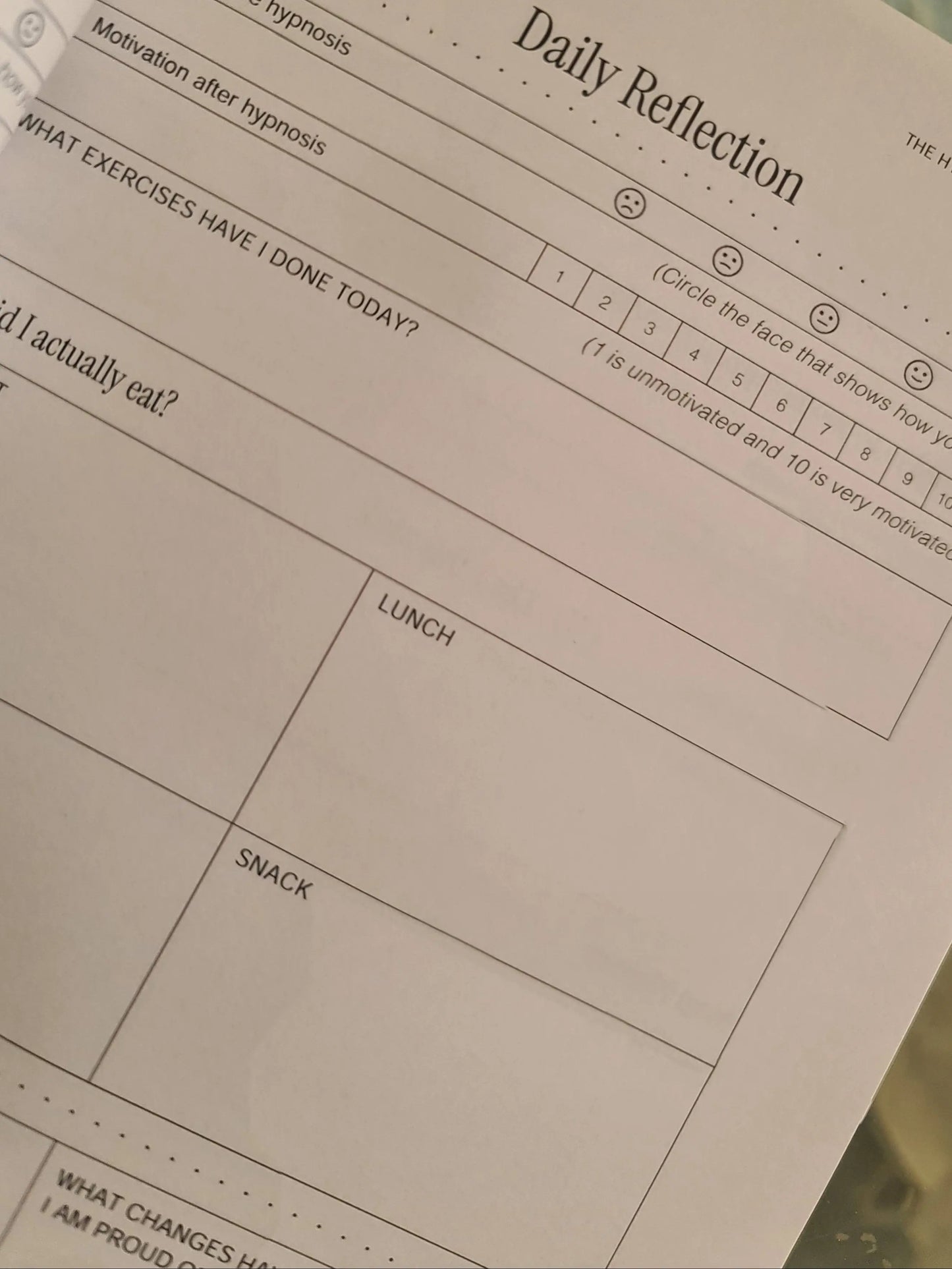 Sheet of paper with 'Daily Reflection' columns on a blurred background